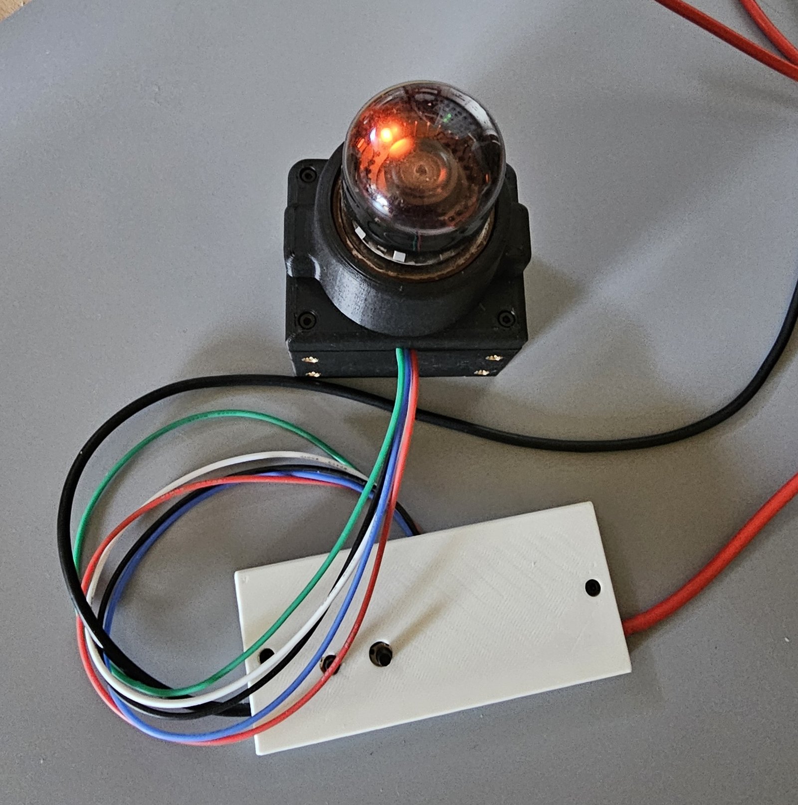 The lit A101 from above: the orange glow near the edge of the ring, the tube in its black socket housing, and the colour-coded wires running to the white clamshell
