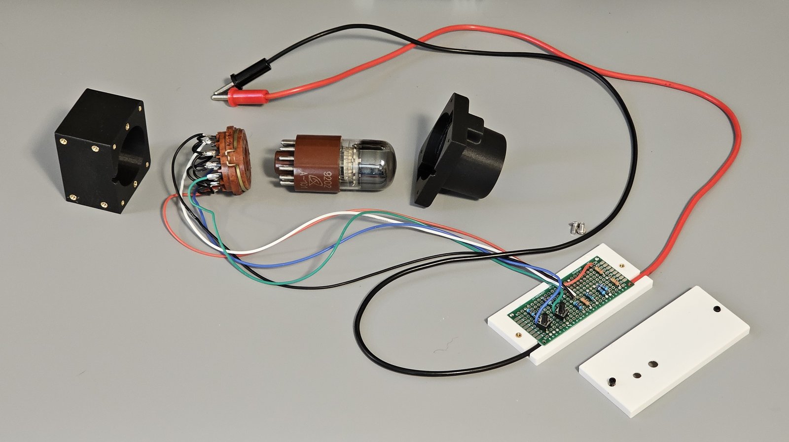 The fixture taken apart: socket housing with its brass inserts, the PL30-2p socket with its wiring, the A101 tube, the shroud, and the opened clamshell showing the perf board with its resistors and pushbuttons