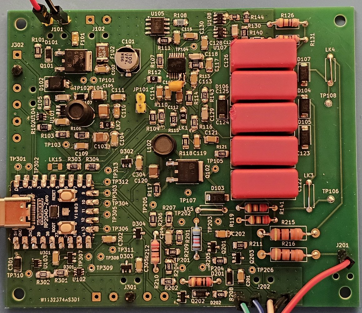 The assembled board 1, top side, in the same orientation: RP2040-Zero soldered in at the lower left, the five red film capacitors of the HV stage at the right, a yellow 470 pF disc capacitor added beside U106, wire links fitted and leads soldered to J101, J201 and J202